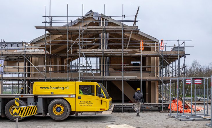 Voorkant van gebouw met stijgers en kraan ervoor