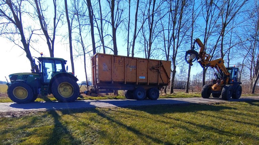 Tractor met aanhanger en voertuig om hout in de aanhanger te tillen