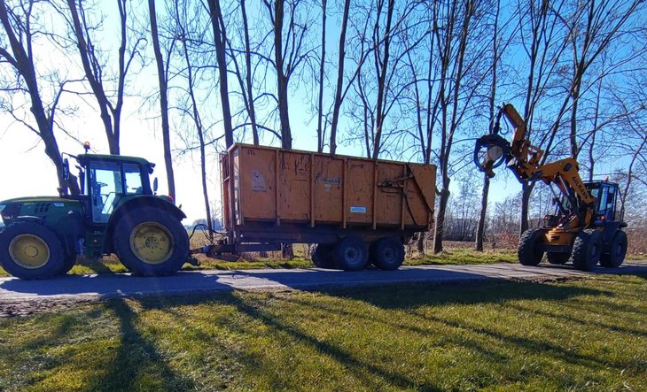 Tractor met aanhanger en voertuig om hout in de aanhanger te tillen