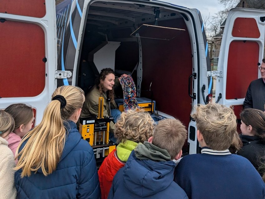 Groep kinderen die uitleg krijgt bij de bus
