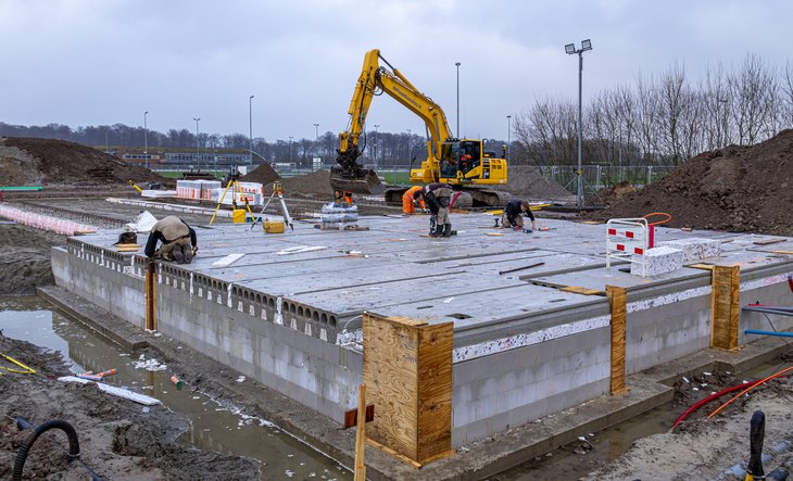 Betonnen fundering met op de achtergrond een graafmachine