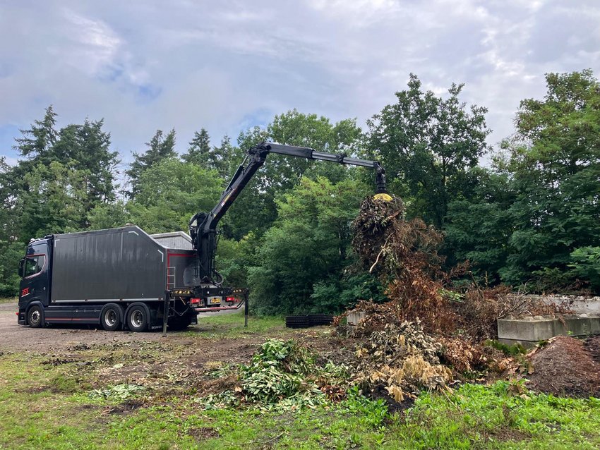 Vrachtwagen met grijparm laadt snoeiafval in