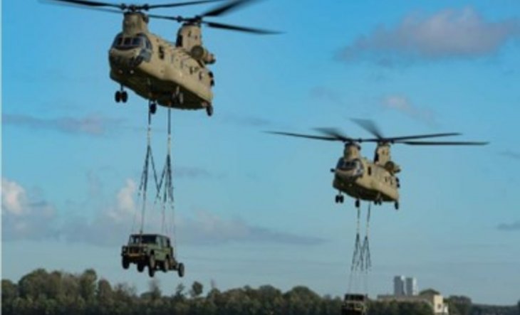 2 Chinook-helikopters in de lucht met auto's eronder